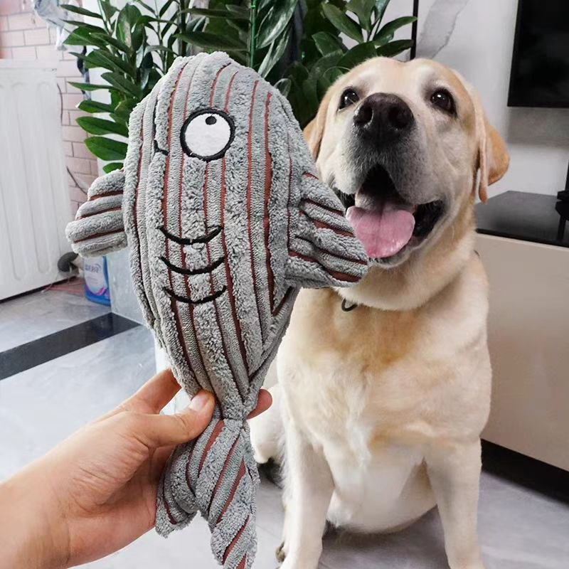 Labrador pictured with a striped fish plush pet toy